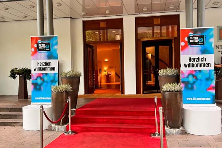 Entrance area of an event venue with red carpet and "Welcome" banners for the SERVIEW TOOL MEETUP.