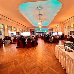 Elegant conference room with round tables, large screens and participants exchanging ideas at the SERVIEW TOOL MEETUP.