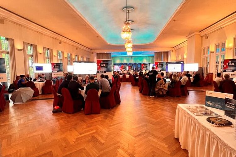 Elegant conference room with round tables, large screens and participants exchanging ideas at the SERVIEW TOOL MEETUP.