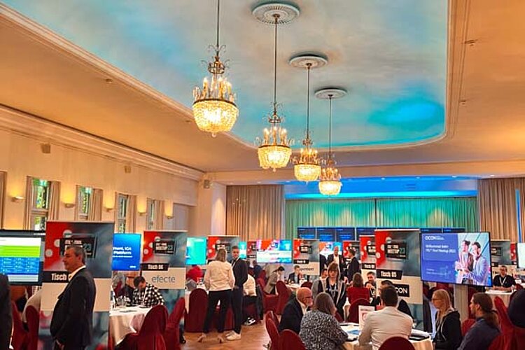SERVIEW TOOL MEETUP participants sit at round tables in an elegant hall with chandeliers and LED ceiling lighting and discuss with exhibitors.