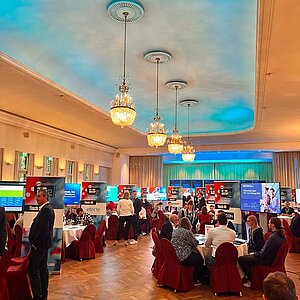 SERVIEW TOOL MEETUP participants sit at round tables in an elegant hall with chandeliers and LED ceiling lighting and discuss with exhibitors.